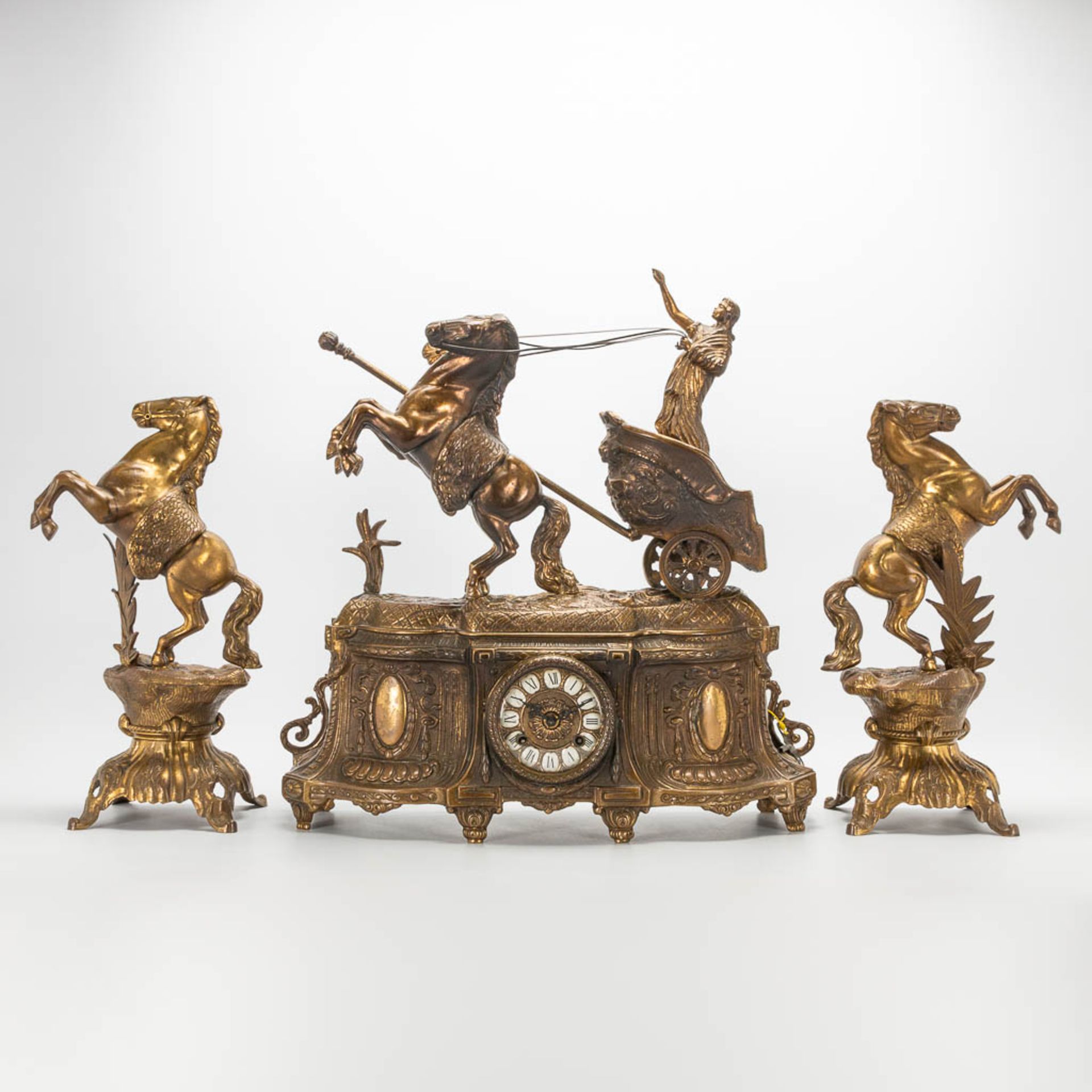 A 3 piece garniture clockset made of bronze, consisting of a clock with battle cart and 2 side piece