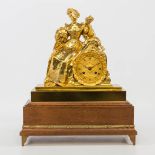 An ormolu gilt table clock on a wood base, with a female figurine holding flowers. 19th century. (16