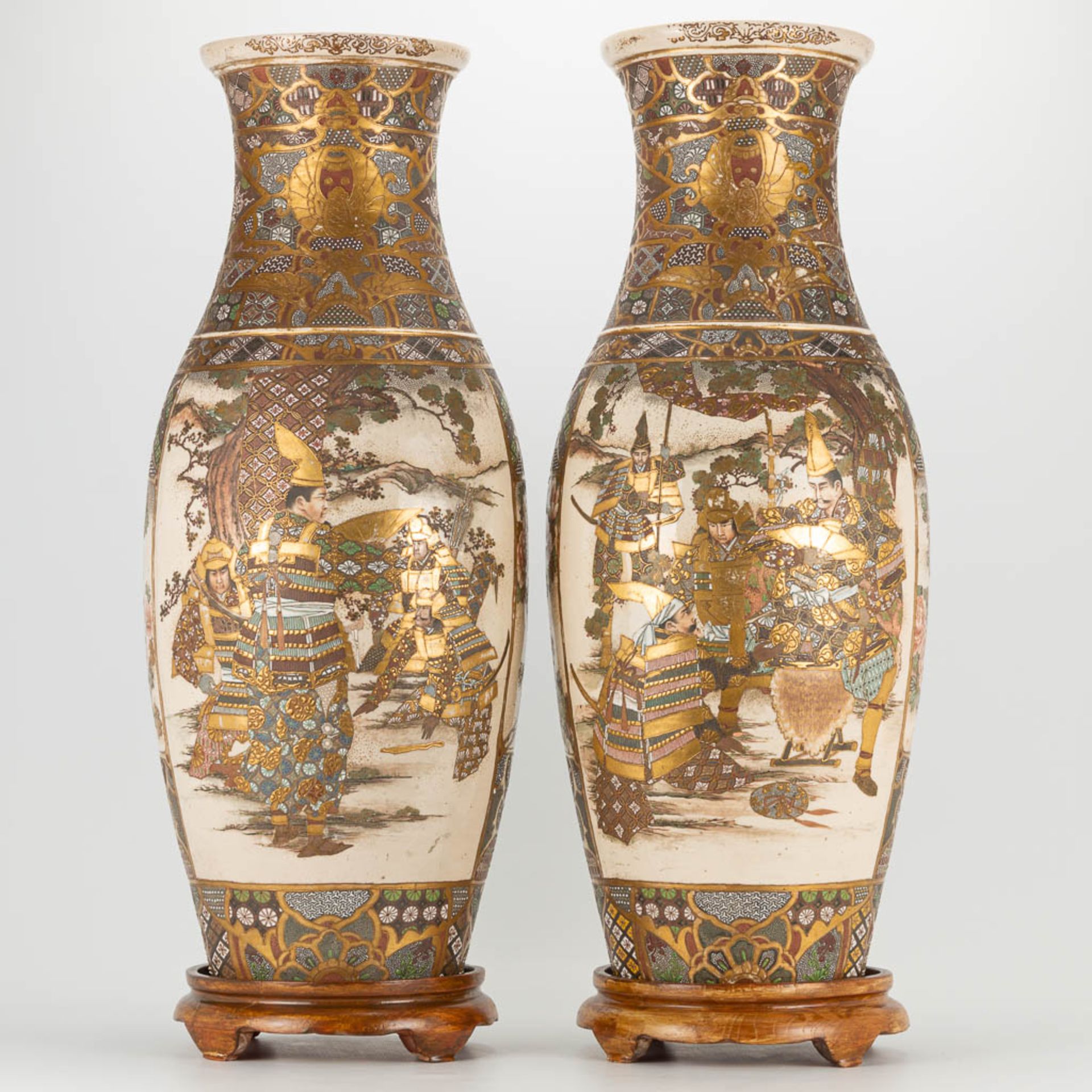 A pair of Japanese Satsuma vases with decor of warriors standing on a wood base. 19th/20th century.