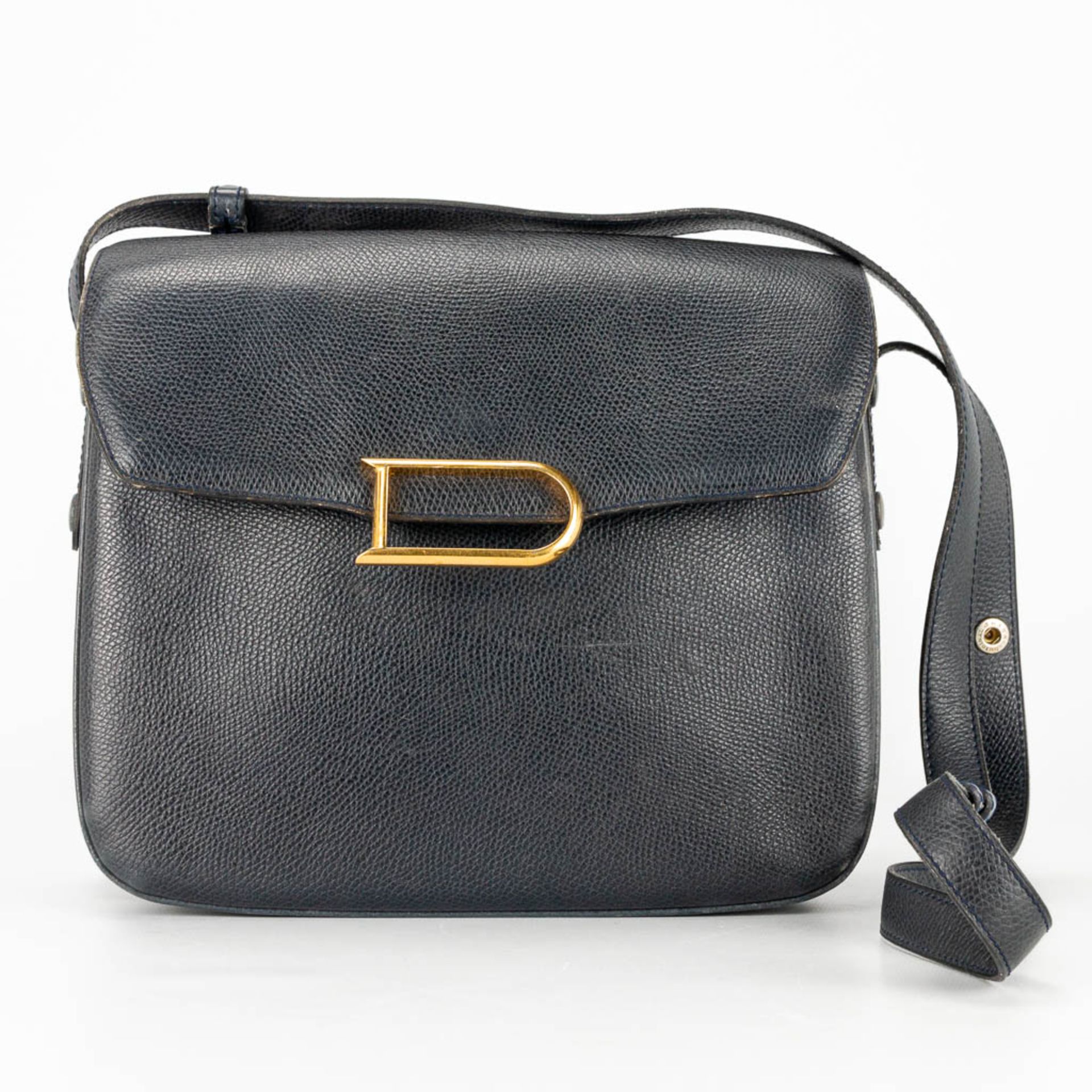A purse made of black leather and marked Delvaux, with the original mirror.