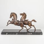 A pair of bronze horses mounted on a marble stand.