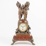 A clock made of red marble with a statue of 2 putti made of spelter