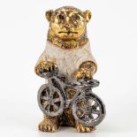 A ceramic figurine of a bear with bicycle, with gold and white glaze. Around 1970.