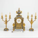 A three-piece mantle clock with candelabra, made of gray marble mounted with gilt bronze.