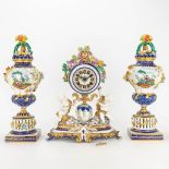 A three-piece garniture clock made of porcelain and marked Svres with hand-painted decor