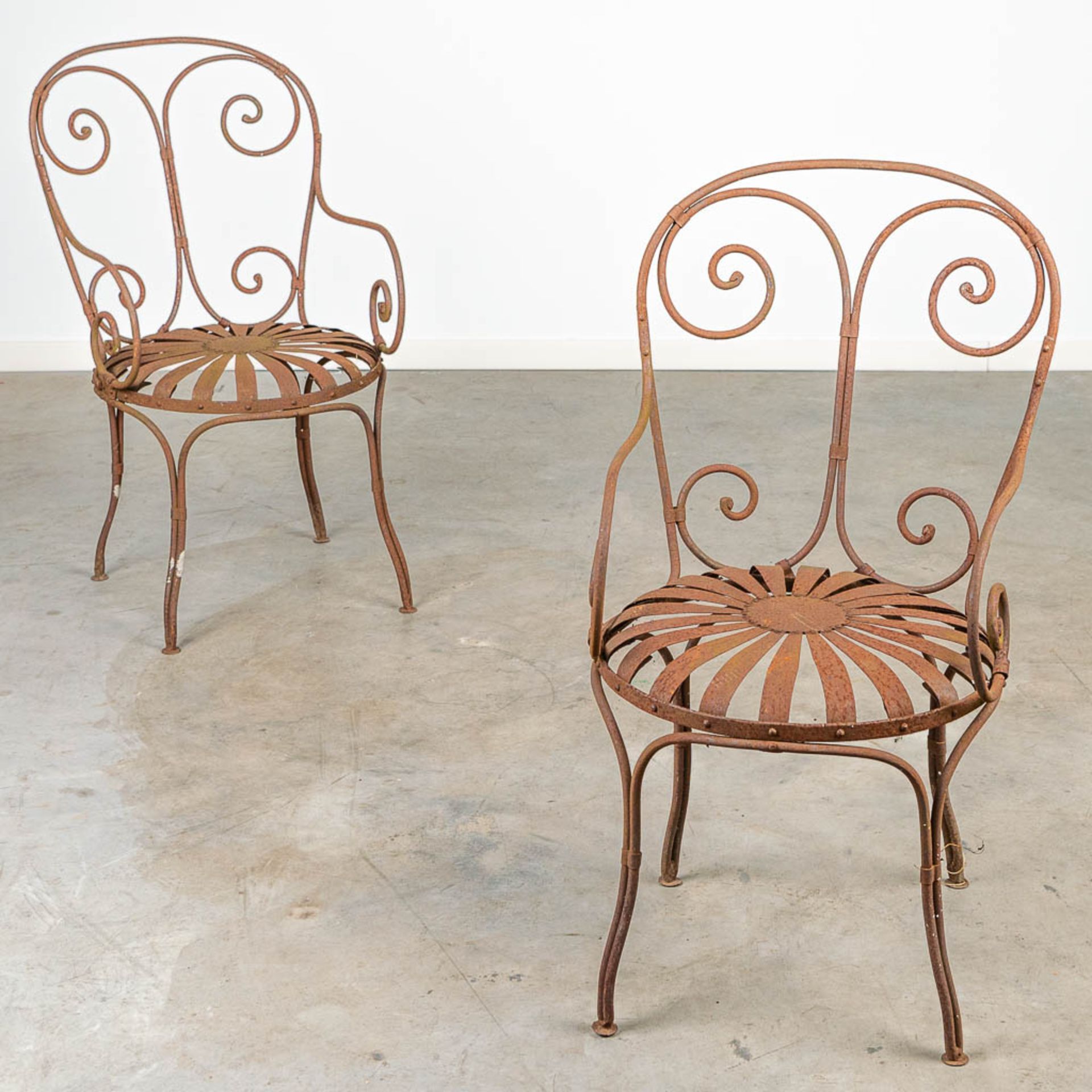A pair of garden chairs made of wrought iron.