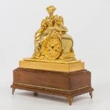 An ormolu wood table clock on a woos base, with a bronze figurine with flowers. 19th century