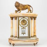 A mantle clock made of alabaster and decorated with a lion in neoclassical style