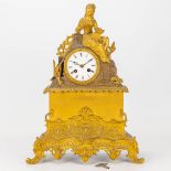 A mantle clock made of gilt bronze and a figurine of a lady and her jewerlybox.