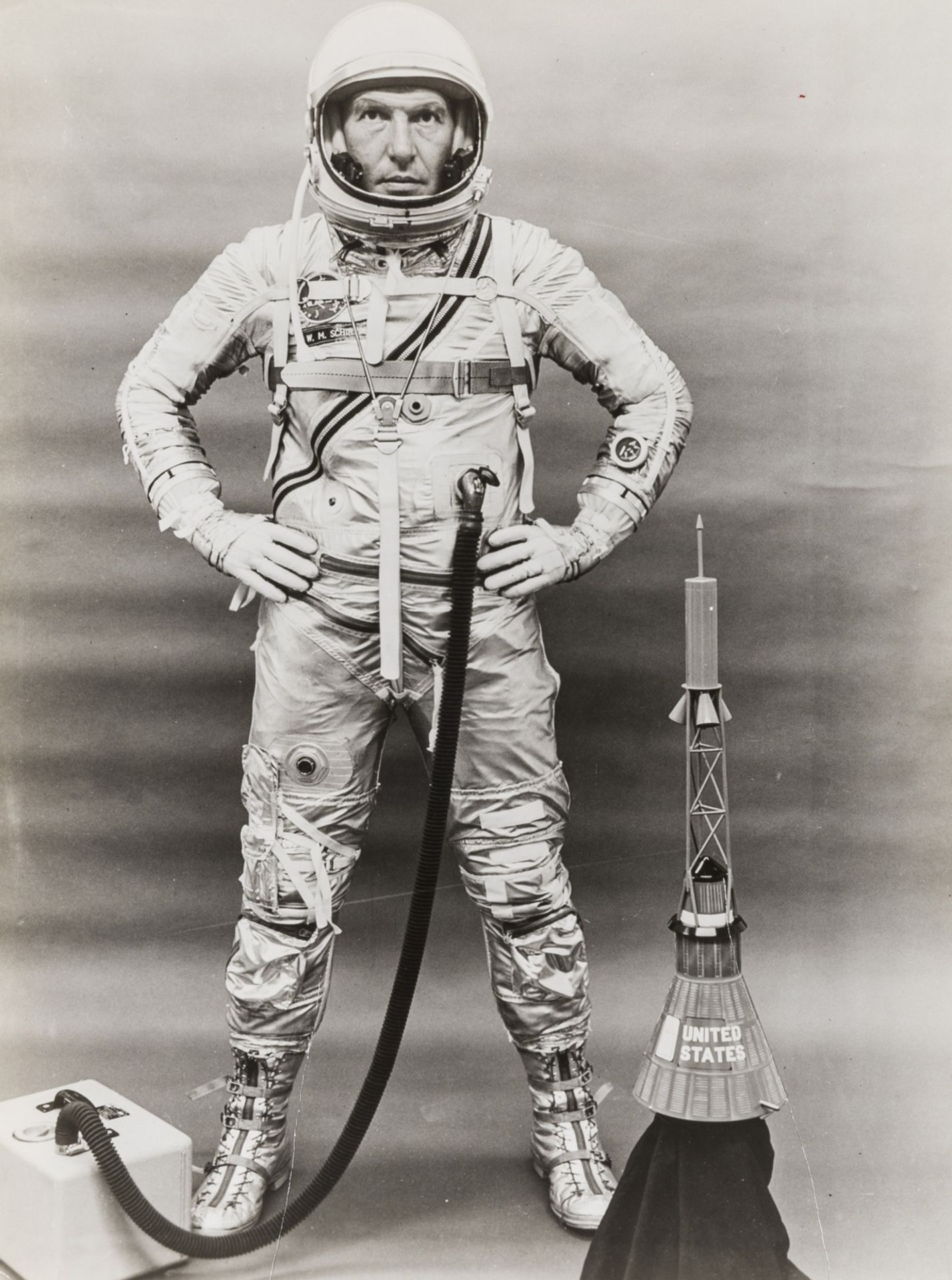 Mercury Astronaut.- Walter Schirra: Pressure suit portrait standing by a spacecraft model, 1962, …