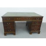 Mahogany veneered desk with a green leather skivver and arrangement of nine drawers, on bracket