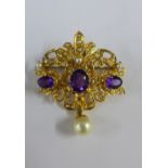 Gold open work brooch / pendant, with a row of three claw set amethysts, the central gemstone