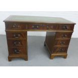 Mahogany veneered desk with green leather skivver and arrangement of nine drawers, on bracket