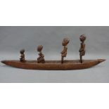 Wooden canoe style boat with four carved figures and an ethnic staff, (a lot) 73cm long
