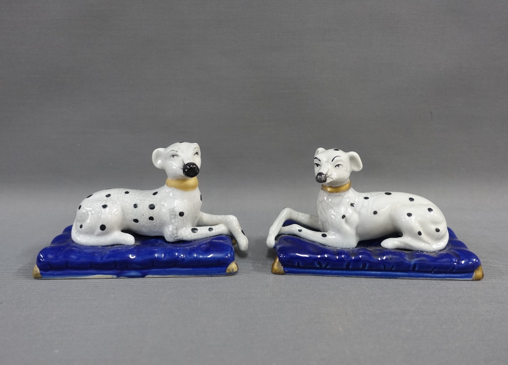 A pair of black and white hounds, on blue rectangular plinth bases, 13cm long (2)