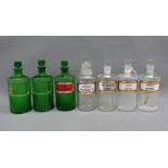 Collection of seven glass pharmacy bottles with some with gilt edged Latin name plates, 23cm high (
