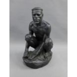 Black painted figure of a seated man, 32cm high