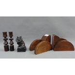 Pair of Art Deco oak bookends, pair of ebonised treen candlesticks and a cast metal cat figure,