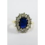 18ct gold sapphire and diamond ring, the claw set sapphire within a surround of twelve round and