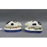 Two Staffordshire black and white glazed rabbits, on blue oval gilt lined bases, 10cm long (2)