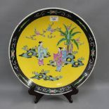 Japanese yellow and black glazed charger, painted with figures in a landscape, 40cm diameter
