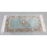 Chinese wool rug, the pale blue ground with central rose sprays with conforming border, fringed