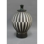 Contemporary studio pottery black and white jar and cover with a striped pattern and circular