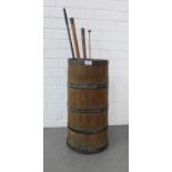 Oak barrel stick stand with metal bands, containing a collection of walking canes and a gun barrel