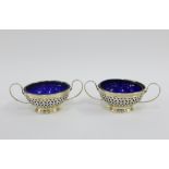 Pair of Edwardian pierced silver and twin handled dishes, with blue glass liners, import marks for