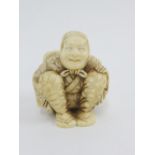 An early 20th century Japanese carved ivory Netsuke of Yakuharai the Oni hunter, modelled seated