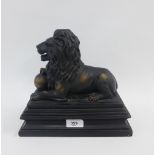 Faux bronze, resin figure of a recumbent lion, on a rectangular plinth, 25 x 23cm