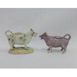 Two Staffordshire cow creamers, one painted with flowers and the other with a lilac lustre glaze,