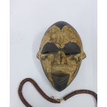 Nigerian Igbo Tribe black and white painted wooden mask, 25cm long together with an African necklace