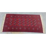 Pakistan rug of Bokhara design, red field with three rows of seven guls, 188 x 97cm
