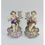Pair of porcelain cherub figural candlesticks, modelled in the manner of Bow, on rococo shell bases,