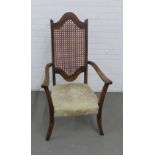 Early 20th century open armchair with a canework back and cream upholstered seat, 63 x 119cm