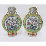 A pair of Chinese moon flask vases, painted with peacocks, flowers and foliage to a famille jaune