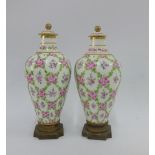 Pair of French porcelain vases with covers, painted with pink and green flowers, on ormolu stands,