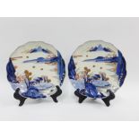 A pair of Japanese Arita plates, with scalloped rims and painted with village scene, 22cm wide (2)