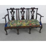 Mahogany triple chair back settee in the Irish Chippendale manner, the serpentine top rails carved