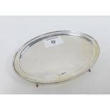 George V silver card tray of oval outline with a beaded edge, on four scroll feet, Chester 1924,