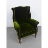Green upholstered wing armchair with mahogany legs on ceramic castors, 80 x 106cm