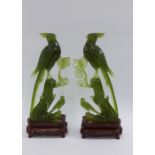 Pair of Chinese green jadeite hand carved bird figures with wooden stands, in a cloth covered