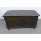 An antique dark oak coffer, the plain hinged top opening to reveal a void interior, with rosette
