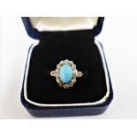 French turquoise and diamond claw set ring, the central oval cabouchon within a surround of fourteen