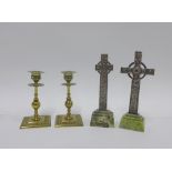 Two white metal Iona crucifix on green hardstone bases and a pair of brass candlesticks, tallest