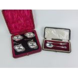 An Edwardian cased set of four silver salts with pierced handles and two matching salt spoons,