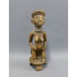 African carved wooden female figure, modelled wearing beads and sitting on a circular base,
