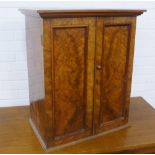 A small burr walnut two cabinet with shelves and single drawer tot he interior, on a plinth base, 62