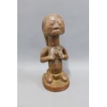 African Tabwa carved wooden female figure, modelled kneeling with body scarifications, 28cm high